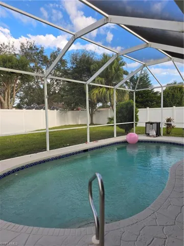 View of swimming pool with glass enclosure, a fenced backyard, and a sunroom