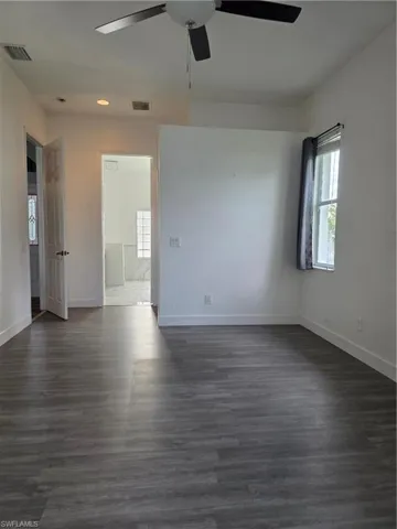 Empty room featuring dark wood-style flooring and a ceiling fan