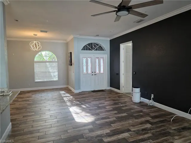 Foyer entrance with ornamental molding, dark wood-style flooring, and a ceiling fan