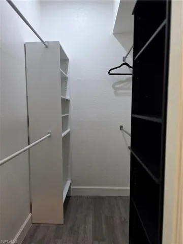 Walk in closet with dark wood-style flooring