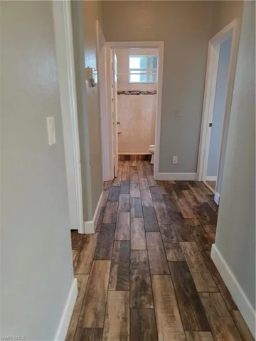 Hallway featuring dark wood-style flooring and baseboards