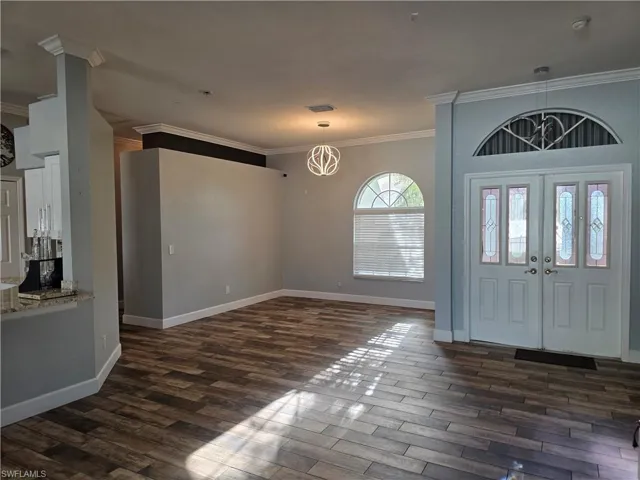 Entrance foyer featuring crown molding and dark wood-style floors