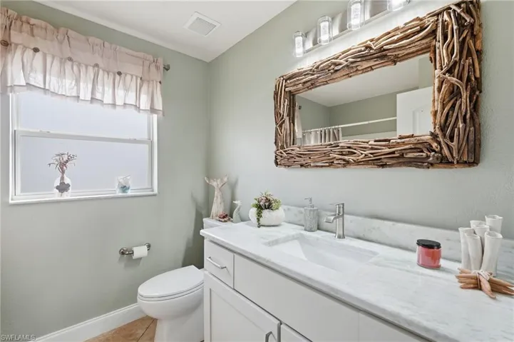 Bathroom featuring a large vanity with white cabinetry, a rectangular undermount sink, and a stone-finish countertop