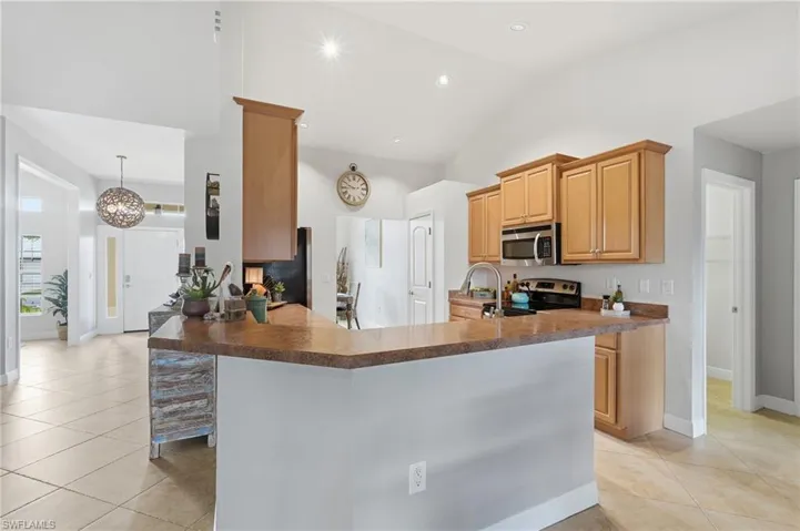 Kitchen featuring a peninsula countertop, wood-finish cabinetry, stainless steel microwave, and an electric range