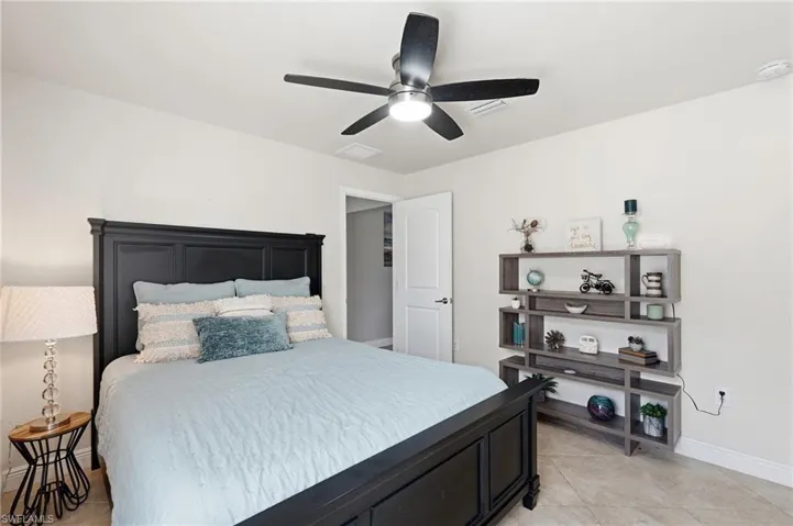 Bedroom featuring tile flooring, a ceiling fan with integrated lighting, and a white paneled door