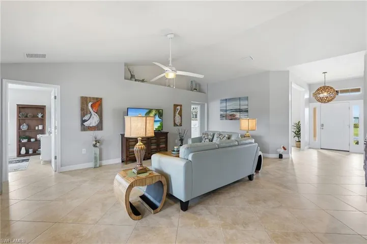 Expansive living area with large format tile flooring, a vaulted ceiling, and an integrated ceiling fan