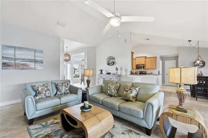 Spacious living area featuring vaulted ceilings, tile flooring, and an integrated ceiling fan with lighting