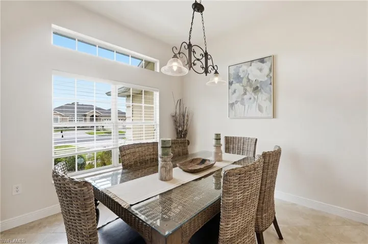 Dining area featuring a large window with horizontal blinds and a transom window above