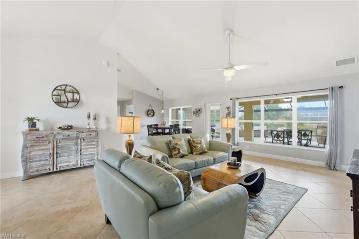 Spacious living area featuring tile flooring, vaulted ceilings, and a ceiling fan