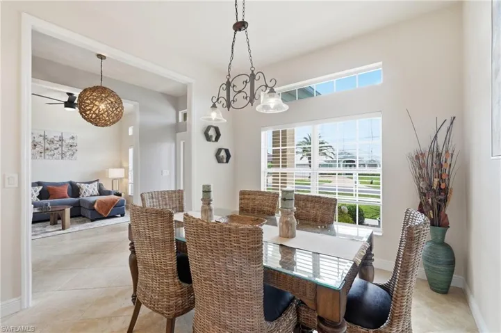 Bright dining space featuring a large window with horizontal blinds and an upper transom window