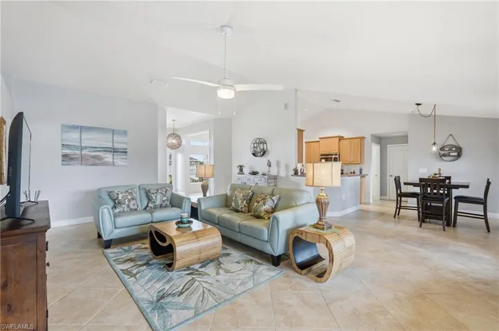 Spacious living area featuring vaulted ceilings, tile flooring, and a ceiling fan
