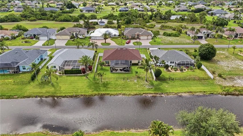 Contemporary single-story residence featuring a screened-in patio, lush green lawn, and mature palm trees
