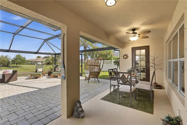 Expansive screened-in lanai featuring a patio paver flooring, overhead ceiling fan, and multiple windows
