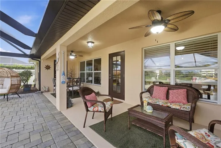 Expansive covered patio featuring two ceiling fans with integrated lighting, a screened enclosure, and paver flooring