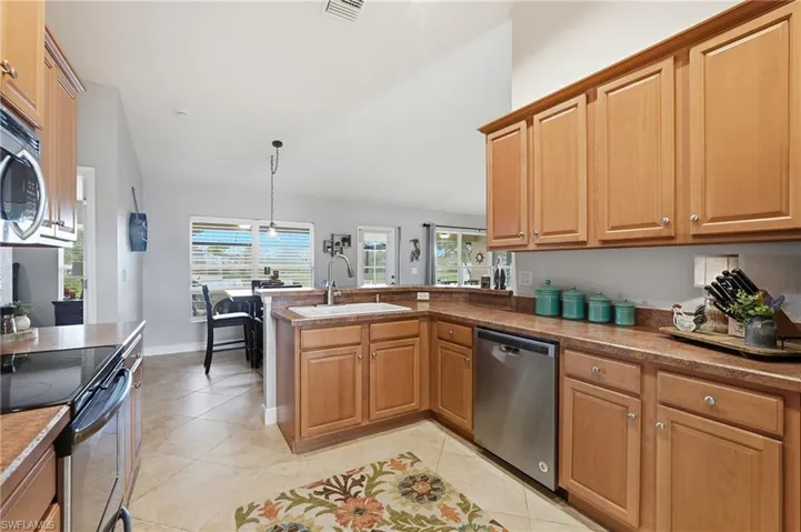Kitchen featuring wood-finish cabinetry, tile flooring, and stainless steel appliances including a built-in microwave, range, and dishwasher