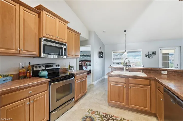 Kitchen featuring wood cabinetry, stainless steel appliances, and a double basin sink with a high-arc faucet