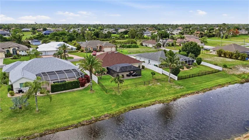 Waterside property featuring expansive green lawn and mature palm trees