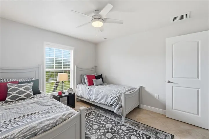 Bright interior with tile flooring, a window with horizontal blinds, a ceiling fan with integrated lighting, and a white paneled door