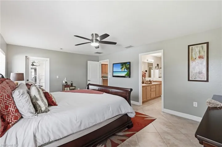 Spacious bedroom featuring tile flooring, light gray wall paint, and a ceiling fan with integrated lighting