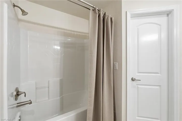 White fiberglass tub and shower combination with brushed bronze fixtures