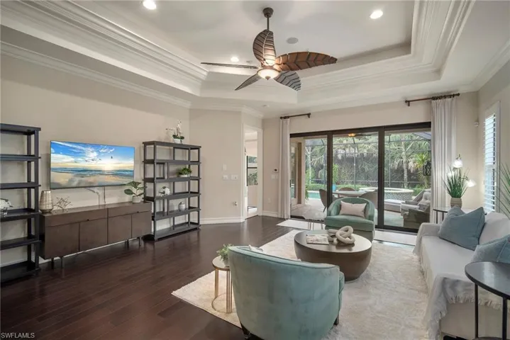 Living room with ceiling fan, a wealth of natural light, hardwood / wood-style floors, and a tray ceiling