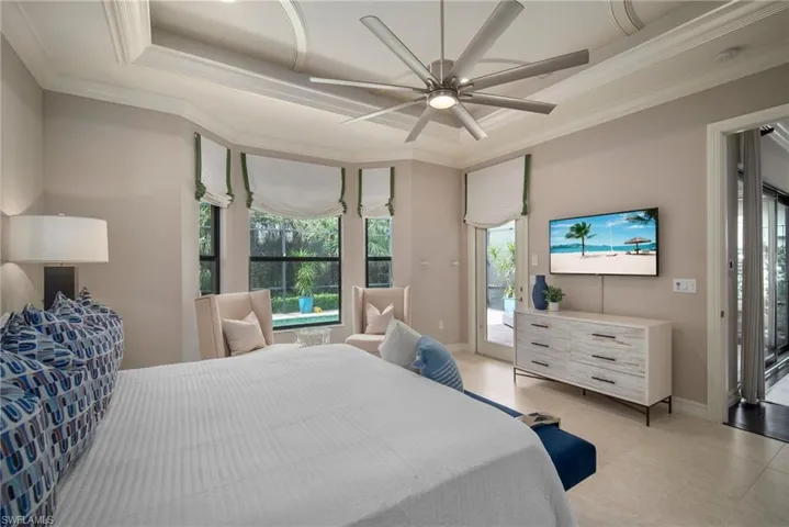 Primary Bedroom featuring crown molding, light tile patterned floors, a tray ceiling, ceiling fan, and access to exterior