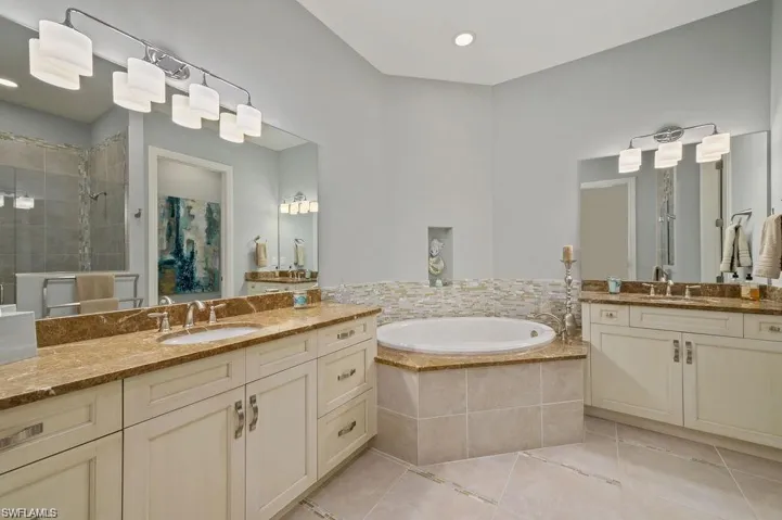 Primary Bathroom with double sink vanity, tile patterned flooring, and separate shower and tub