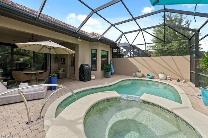 View of swimming pool with an in ground hot tub, a lanai, and a patio