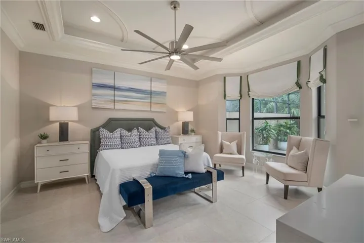 PrimaryBedroom with ceiling fan, a raised ceiling, ornamental molding, and light tile patterned floors