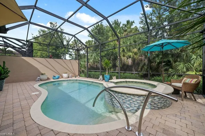 View of pool featuring screen enclosure, an in ground hot tub, and a patio area