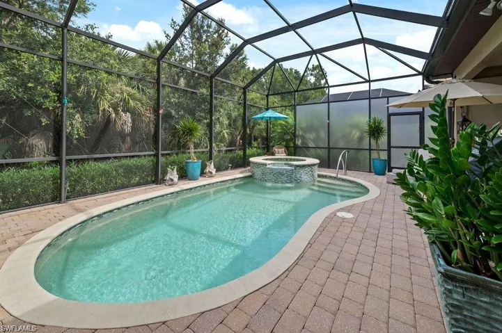 View of pool with screen enclosure, an in ground hot tub, and a patio