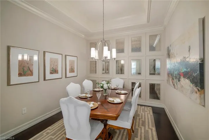 Dining area with crown molding, dark hardwood / wood-style flooring, a chandelier, and a raised ceiling