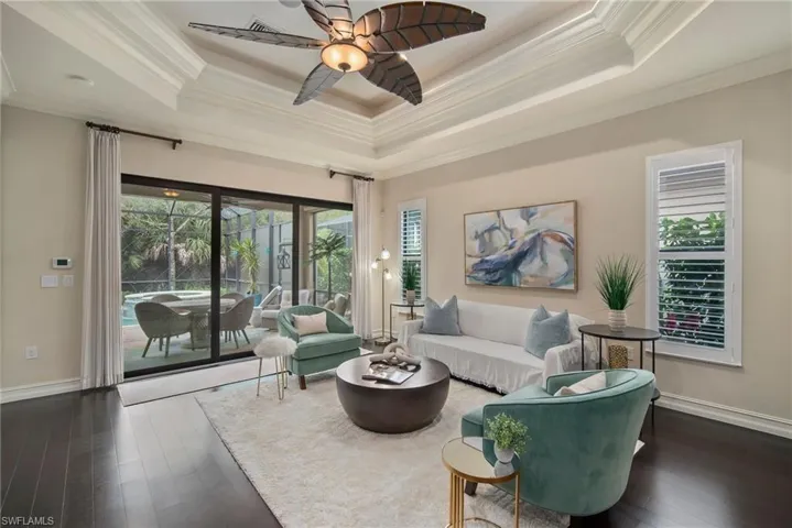 Living room with ceiling fan, ornamental molding, hardwood / wood-style flooring, and a raised ceiling