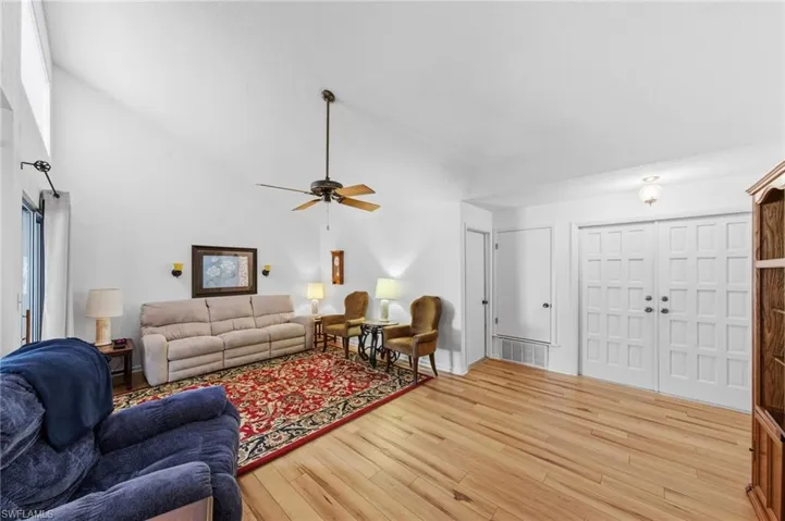 Living room featuring vaulted ceilings, upgraded flooring in 2021 and fans.