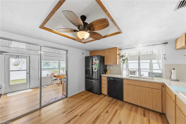 The kitchen is well-appointed with Corian solid surface countertops, tile backsplash, instant hot water dispenser, dishwasher, cooktop, built-in wall oven, and microwave. (Refrigerator does not convey with sale)