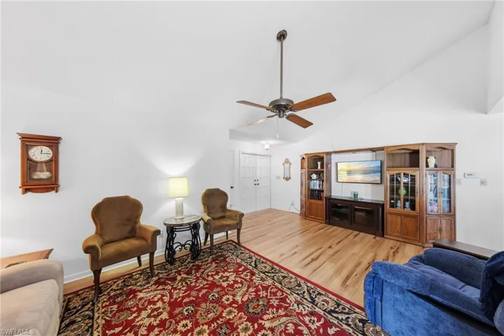 Living room featuring vaulted ceilings, upgraded flooring in 2021 and fans.