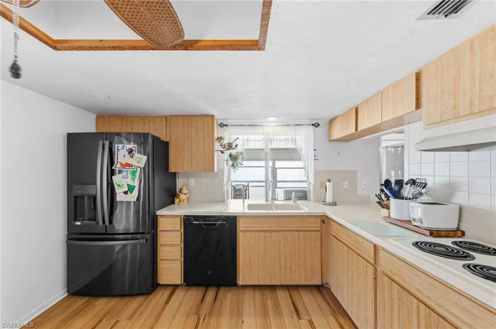 The kitchen is well-appointed with Corian solid surface countertops, tile backsplash, instant hot water dispenser, dishwasher, cooktop, built-in wall oven, and microwave. (Refrigerator does not convey with sale)