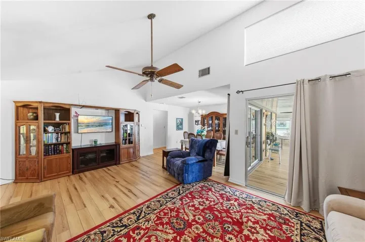 Living room featuring vaulted ceilings, upgraded flooring in 2021 and fans.