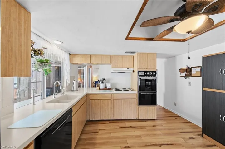The kitchen is well-appointed with Corian solid surface countertops, tile backsplash, instant hot water dispenser, dishwasher, cooktop, built-in wall oven, and microwave. (Refrigerator does not convey with sale)