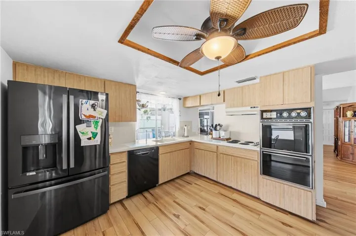 The kitchen is well-appointed with Corian solid surface countertops, tile backsplash, instant hot water dispenser, dishwasher, cooktop, built-in wall oven, and microwave. (Refrigerator does not convey with sale)