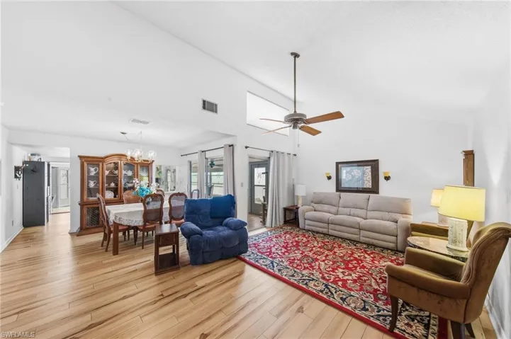 Living room featuring vaulted ceilings, upgraded flooring in 2021 and fans.