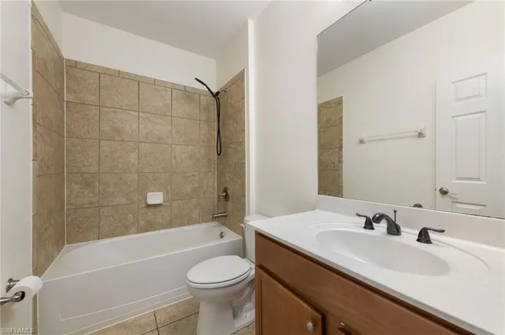 Bathtub with subway tile surround, vanity with integrated sink, and dark bronze-finish fixtures