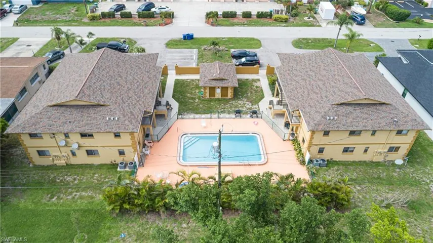 Multi-unit property featuring two two-story buildings, a central swimming pool, and a fenced pool deck