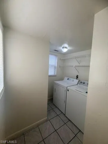 Dedicated laundry area featuring tile flooring, built-in wire shelving, and a window for natural light