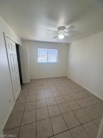 Spacious room featuring neutral tile flooring, light-colored walls, and a window with blinds