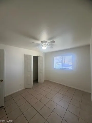 Bright interior space featuring tiled flooring, a window with blinds, and a ceiling fan