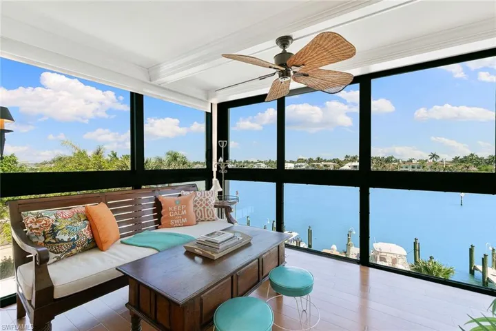Sunroom featuring expansive windows, plenty of natural light, a water view, beam ceiling, and ornamental molding