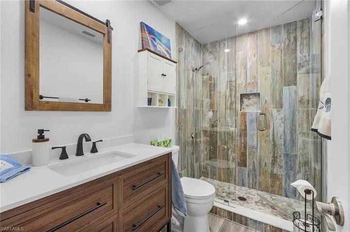Guest bathroom with solid surface vanity, toilet, and a glass enclosed shower.