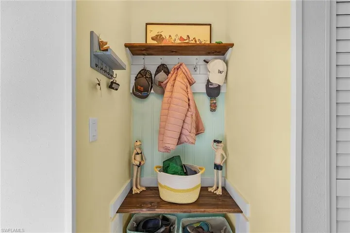 View of mudroom with coat storage and bench for slipping on shoes.