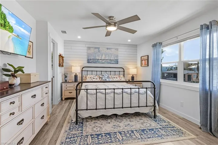Bedroom featuring light, wood-style, luxury vinyl flooring and modern style ceiling fan.  Partial Beach views from this bedroom.